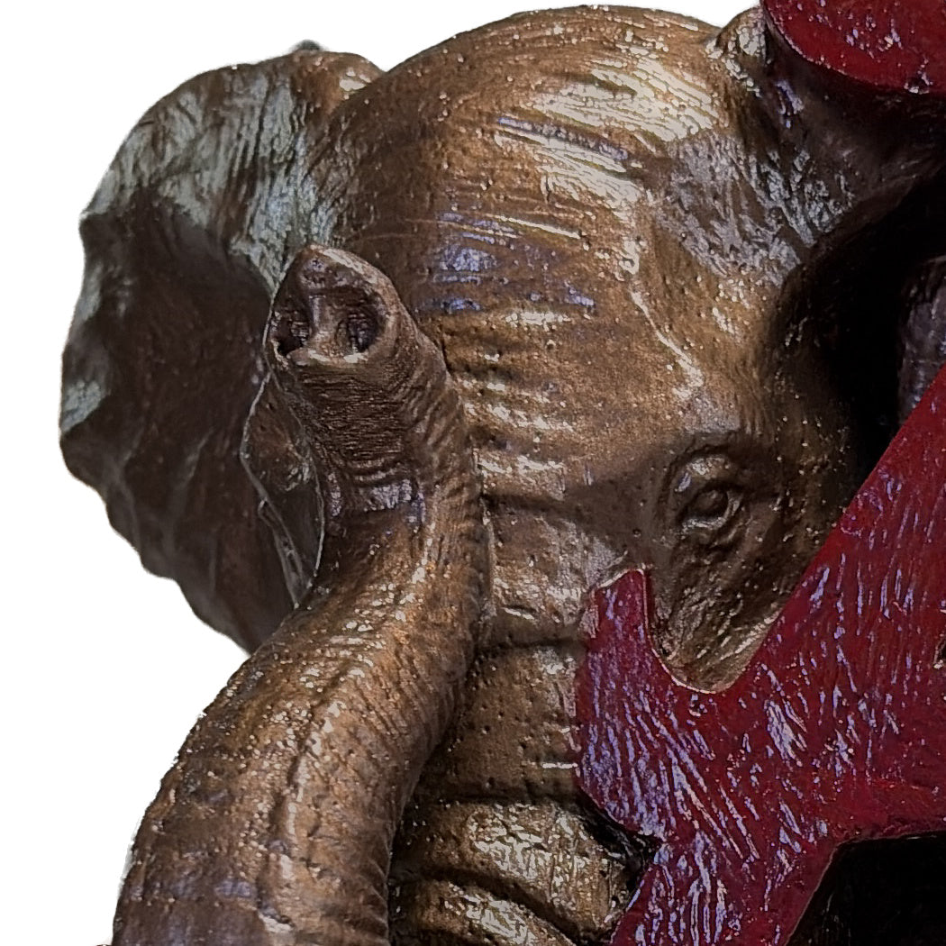 Close-up of the sculpted elephant face, eye and ear on the Alabama Crimson Tide elephant and script A desk sculpture, bronze metal coating